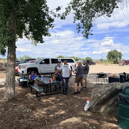 Picnic tables and trucks pulled up under the trees
